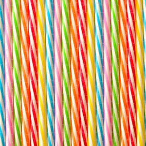 May include: A close-up shot of colorful, striped candy sticks. The sticks are arranged vertically, showcasing a variety of colors including red, orange, yellow, green, blue, and pink, with white stripes. The candy sticks have a glossy finish.