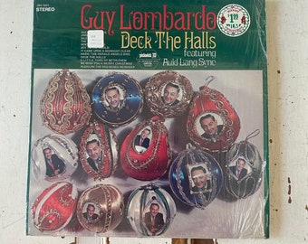 May include: A vintage vinyl record album cover featuring a green background with a photo of Guy Lombardo and his orchestra. The album title is "Deck The Halls" and features a photo of the band members in a collage of Christmas ornaments. The album cover also includes the text "Pickwick 33" and "Auld Lang Syne".