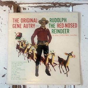 May include: Vintage vinyl record album cover featuring Gene Autry in a cowboy hat and red shirt. The album is titled "Rudolph the Red-Nosed Reindeer" with a Christmas theme, including Santa and reindeer.