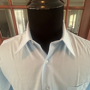 May include: A light blue dress shirt with a button-down collar and a single button closure.