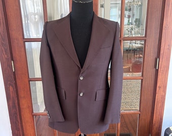Peut inclure: Un blazer marron à fermeture simple et deux poches à rabat. Le blazer a un col cranté et est fait d'un tissu lisse.