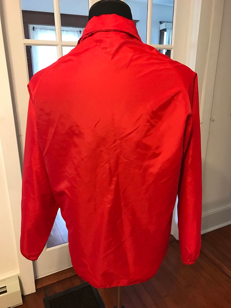 May include: A red lightweight jacket with a zipper closure and long sleeves.