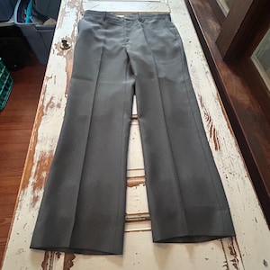 Könnte beinhalten: Eine graue Anzugshose mit geradem Bein. Die Hose hat einen dezenten Nadelstreifen und ein klassisches Design.