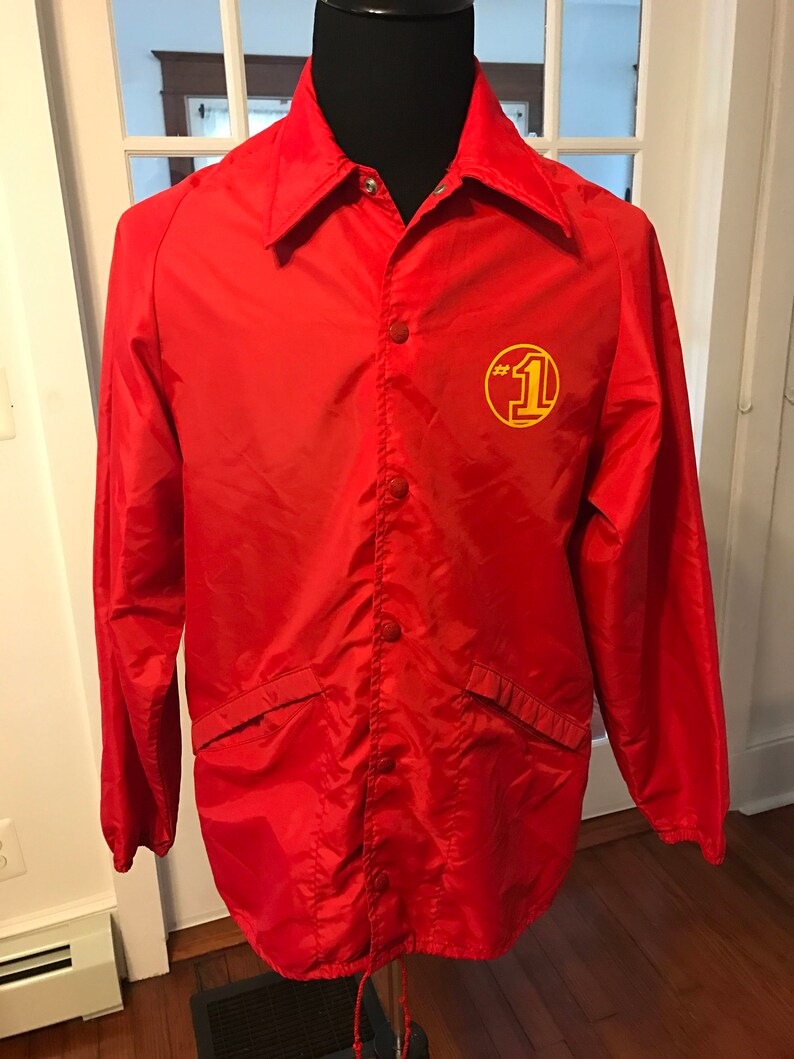 May include: Red nylon jacket with a yellow circle logo that says "#1" on the right side of the chest.