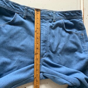 May include: A pair of light blue denim jeans with a wooden ruler measuring 15 inches. The jeans have a high waist and a straight leg.