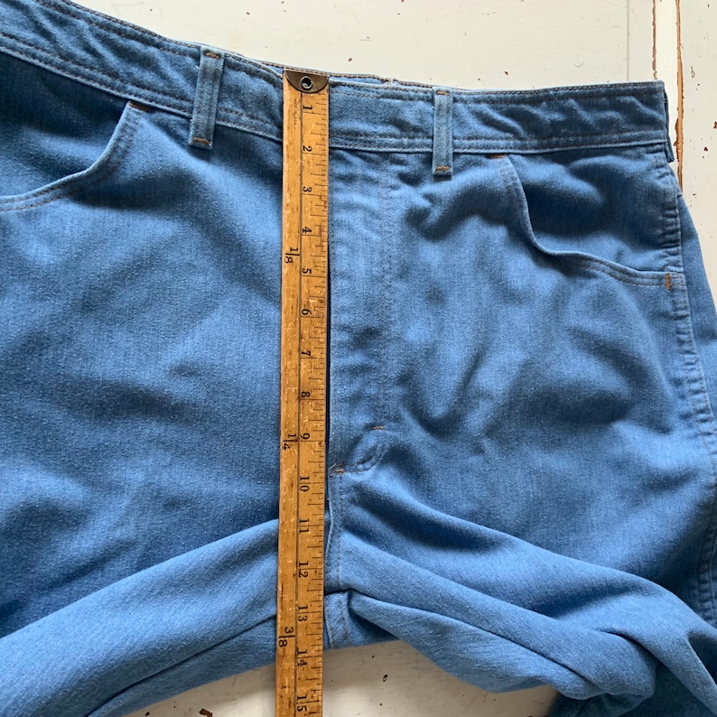 May include: A pair of light blue denim jeans with a wooden ruler measuring 15 inches. The jeans have a high waist and a straight leg.