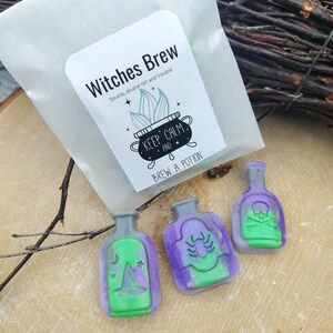 May include: Three small green and purple glass bottles with different witchy designs. The bottles are labelled "Keep Calm and Brew a Potion".