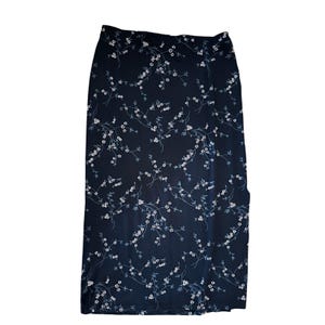 May include: A long, dark blue skirt with a floral pattern. The skirt features a repeating design of white flowers and thin, light blue stems. The skirt is made of a lightweight fabric and has a straight, flowing silhouette.