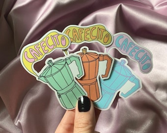 May include: Three colorful stickers featuring a cartoon illustration of a coffee pot with the word "Cafecito" written in a whimsical font.