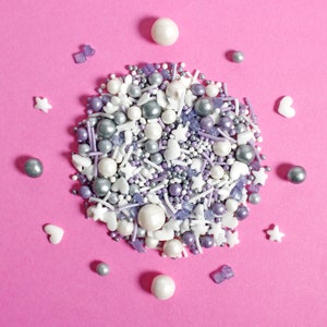 Purple, silver and white cake sprinkles featuring edible stars, hearts, sugar strands, nonpareils, sugar rocks and pearls.