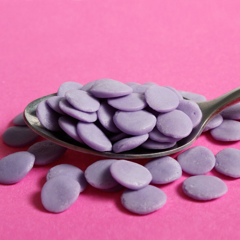 Purple jumbo confetti sequin shaped edible cake sprinkles on a spoon.