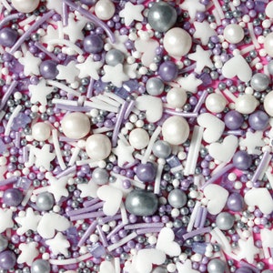 Purple, silver and white cake sprinkles featuring edible stars, hearts, sugar strands, nonpareils, sugar rocks and pearls.