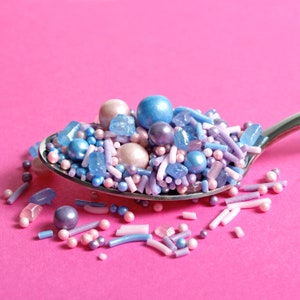 Purple, pink and blue cake sprinkles on a spoon.