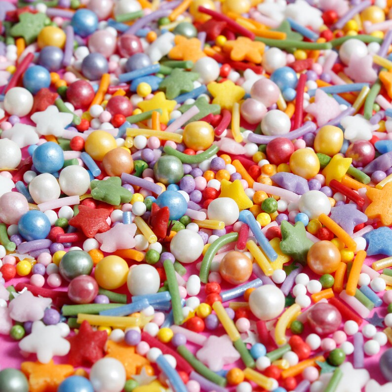 White, orange, red, purple, yellow, blue white cake sprinkles featuring edible sugar strands, nonpareils, sequins and pearls.