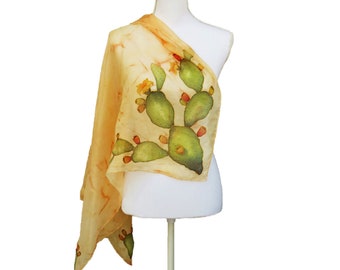 Puede incluir: Una bufanda de seda amarilla con un diseño pintado a mano de un cactus chumbera con almohadillas verdes y flores amarillas.
