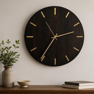 May include: A circular wall clock featuring a dark brown, wood-grain textured face with gold-colored hour markers and thin gold hands. The clock has a clean, simple design with no numbers, displaying a minimalist aesthetic with its dark finish.