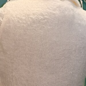 May include: A white fluffy sweater with a collar and a button fastening.