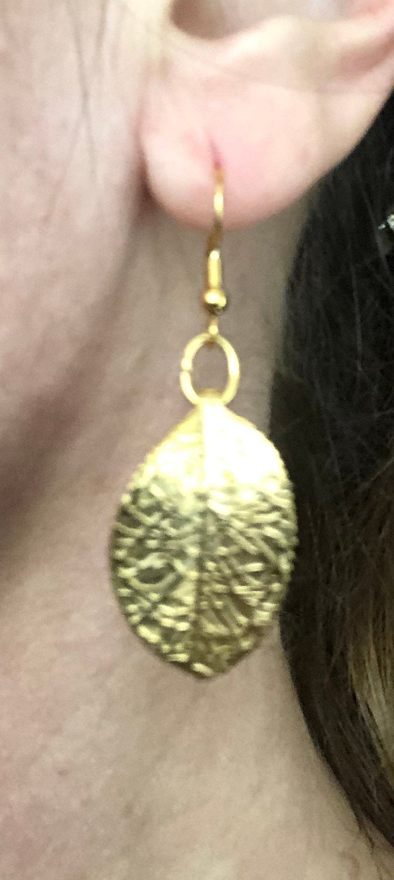 Puede incluir: Pendientes de hoja de oro con superficie texturizada.