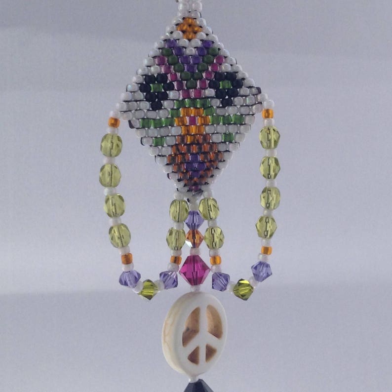 May include: A beaded peace sign charm with a white peace symbol pendant, green, orange, and purple beads, and a diamond-shaped beaded top.
