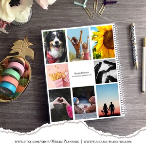 May include: A spiral-bound planner with a collage of photos, including a dog, people at the beach, a sunflower, and a couple at sunset. A gold pineapple-shaped dish holds colorful washi tape rolls. Two pens and paper clips are also visible.