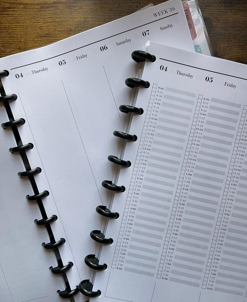 May include: Close-up of open planner pages with a black disc-bound spine. The pages are white with gray grid lines and time slots. The top of the page shows the days of the week, with "Thursday" and "Friday" visible. The planner is open to "Week 36".
