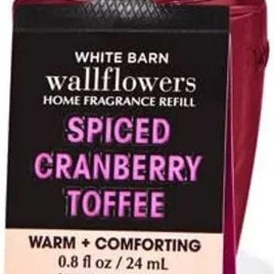 May include: A clear glass bottle with a black cap and a pink label. The label says "White Barn wallflowers Home Fragrance Refill Spiced Cranberry Toffee Warm + Comforting 0.8 fl oz / 24 mL Caution: Eye Irritant. Read Inside Carefully."