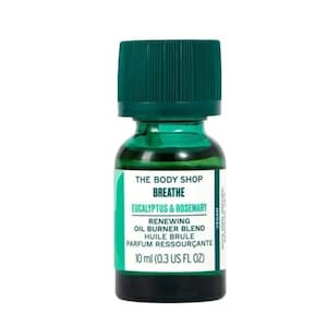 Pode incluir: Uma garrafa de vidro verde de The Body Shop Breathe Eucalyptus & Rosemary Renewing Oil Burner Blend. A garrafa é etiquetada com o nome do produto e os ingredientes, e contém 10 ml (0.3 US fl oz).