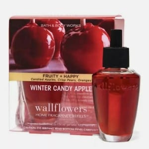 Puede incluir: Una botella de vidrio roja de recarga de fragancia para el hogar Wallflowers Winter Candy Apple. La botella está etiquetada con el logotipo de Bath & Body Works y la descripción de la fragancia: "Fruity + Happy Candied Apples, Crisp Pears, Oranges".