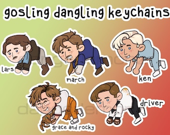 May include: A collection of five cartoon keychains featuring stylized illustrations of Ryan Gosling characters. Each keychain is depicted in a crawling pose, with names like "Lars," "March," and "Ken" below each character. The text "gosling dangling keychains" is at the top.