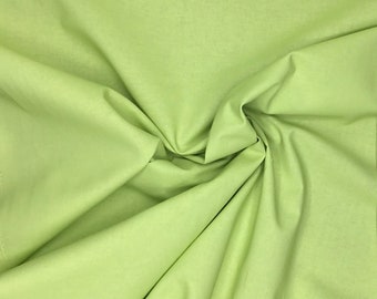 May include: A close-up shot of a light green fabric with soft folds and creases. The fabric has a smooth texture and a solid color, with varying shades of green due to the folds. The material appears to be a lightweight textile.