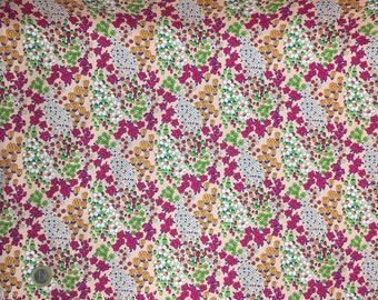 Pode incluir: Tecido floral com fundo pêssego e um padrão repetitivo de pequenas flores brancas, fúcsia, verdes e amarelas. O tecido tem um design denso e completo, adequado para vários projetos de costura.