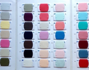 May include: A fabric colour chart displaying numerous swatches in beige, pink, blue, green, and purple hues. A larger fabric sample is on the left. Each swatch is labelled with a number and the letter "L".
