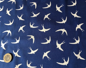 May include: Close-up of a navy blue fabric with a repeating pattern of white swallows. The swallows are depicted in flight, creating a dynamic and airy design. The fabric's texture is visible, suggesting a soft material.