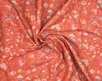 May include: Close-up of a floral fabric with a burnt orange background. The fabric is covered in a pattern of small flowers in shades of pink, white, yellow, and blue, with green leaves. The fabric is gathered in soft folds.
