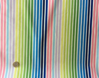 May include: A fabric with vertical stripes in a rainbow of colors, including pink, blue, green, and yellow, with white stripes separating them. The fabric is slightly wrinkled, suggesting it is a textile material.