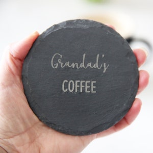 Puede incluir: Un posavasos de pizarra negra con el texto "Grandad's Coffee" grabado en plata.