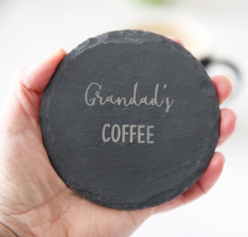 Puede incluir: Un posavasos de pizarra negra con el texto "Grandad's Coffee" grabado en plata.