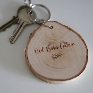 May include: A wooden keyring with the text "Old Barn Cottage" engraved on it. The keyring is attached to a silver key ring with two keys.