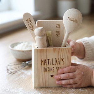 May include: A wooden children's baking set. The set includes a box with the text "MATILDA'S BAKING SET" and a star, plus a spoon, spatula, brush, and rolling pin, each engraved with the name "MATILDA".