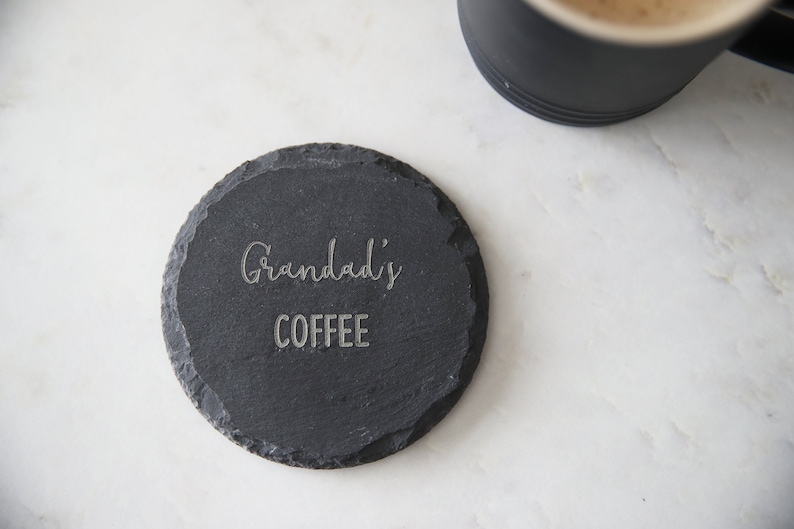 Puede incluir: Un posavasos de pizarra negra con el texto "Grandad's Coffee" grabado en &eacute;l.