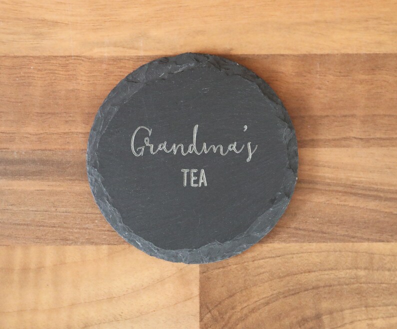 May include: A black slate coaster with the text "Grandma's Tea" engraved in silver.