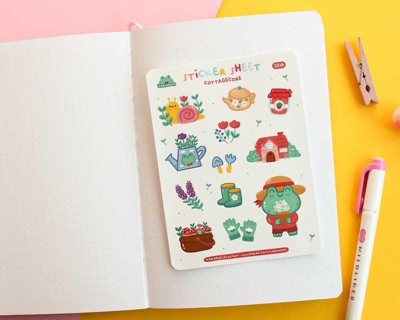 Pode incluir: Uma folha de adesivos com tema cottagecore. A folha apresenta ilustra&ccedil;&otilde;es de sapos, carac&oacute;is, flores, um bule de ch&aacute;, um pote de geleia, uma casa, botas, luvas de jardinagem e cogumelos. O texto "STICKER SHEET" e "COTTAGE CORE" est&aacute; impresso na folha.