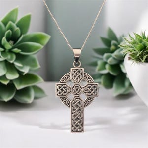 May include: A silver Celtic cross pendant necklace with intricate knotwork design. The pendant is suspended from a silver chain.