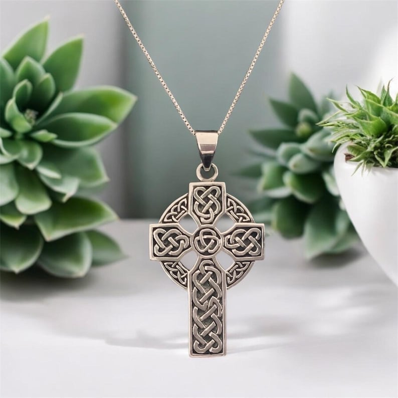 May include: A silver Celtic cross pendant necklace with intricate knotwork design. The pendant is suspended from a silver chain.