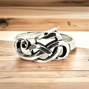 Puede incluir: Anillo de plata con un diseño detallado de un dragón entrelazado con un nudo.