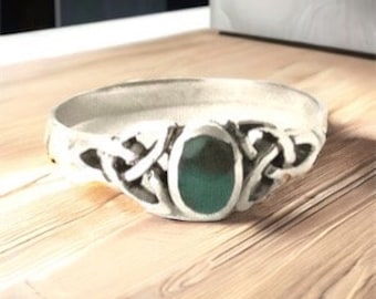 May include: A silver Celtic knot ring with a green oval stone in the center.