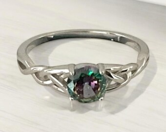 May include: A silver ring with a twisted band design and a round, iridescent green gemstone.