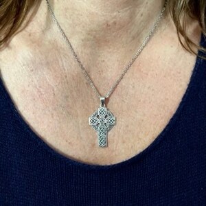 May include: A silver Celtic knot cross pendant necklace. The cross is detailed with intricate knotwork and hangs from a silver chain.