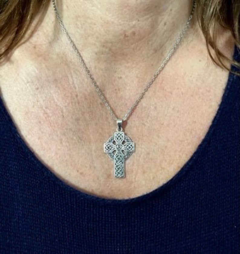 May include: A silver Celtic knot cross pendant necklace. The cross is detailed with intricate knotwork and hangs from a silver chain.