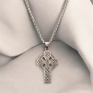May include: A silver chain necklace with a Celtic cross pendant. The cross is intricately designed with a knotwork pattern.